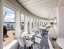 Sky Lounge seating situated next to large glass windows with panoramic views aboard American Cruise Lines' American Patriot.