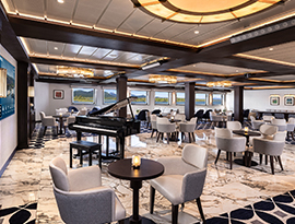 A sophisticated ship lounge featuring a black grand piano, marble flooring, clustered armchairs with small tables, and windows offering a scenic view of the water.