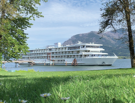 American Song docked along the Columbia River in Richland, where small white flowers peak out from the tall grass