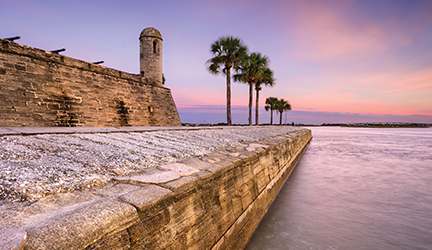 Historic stone walls of Castillo de San Marcos along the waterfront in St. Augustine at sunrise, viewed during a coastal excursion from an American Cruise Lines itinerary