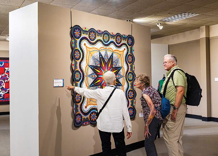 Cruise guests viewing colorful quilt exhibits at the National Quilt Museum during a Paducah port stop, showcasing intricate fiber art and craftsmanship.