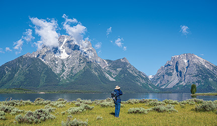 Guest taking a photo of the Grand Teton Mountains under clear blue skies.