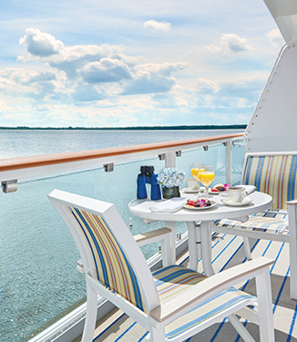 Private balcony on an American Cruise Lines ship with a table set for breakfast, overlooking the waters of the Great Lakes.