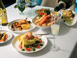 Elegant dining setup with gourmet dishes, wine, and champagne on board an American Cruise Lines ship.