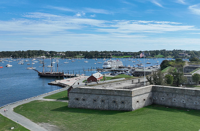 Fort Adams in the foreground with a tall ship and American Cruise Lines ship docked farther back.