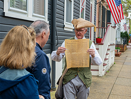 A costumed historical interpreter holds up a replica document for guests during an American Cruise Lines guided excursion along the Southeast Sea Islands route.