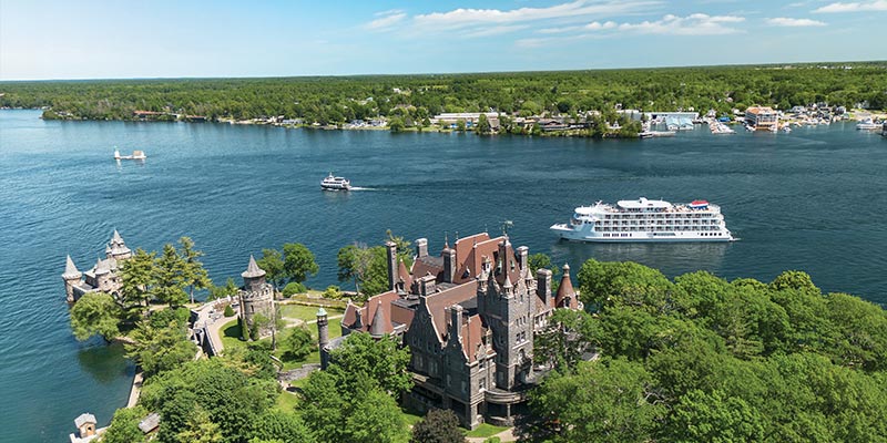 American Patriot cruise ship on one of the Great Lakes, surrounded by scenic shoreline, under a clear blue sky.