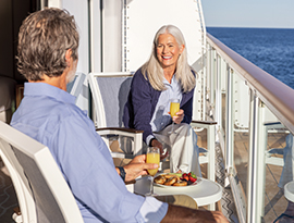 An older couple enjoys drinks on the private balcony of an American Cruise Lines small coastal ship as they cruise past the scenic coastal waters of the Southeast Sea Islands.