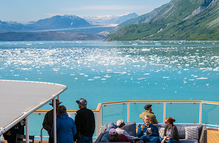 A crisp white glacier above the surface of the blue, icy waters of Glacier Bay Basin under a bright blue sky.