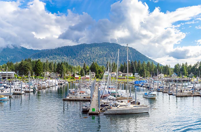 The snow-capped mountains create the backdrop for the colorful buildings and tall pine trees alongside Frederick Sound in Petersburg.