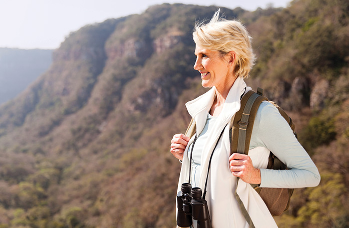 Guest with backpack and binoculars enjoying a scenic nature excursion during a Columbia River cruise near St. Helens, Oregon.