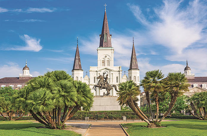 A statue of a cannon in Washington Artillery Park with the St. Louis Cathedral in the background.