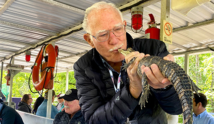 A man holds and kisses a small alligator while aboard a boat ride on the bayou.