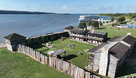 A cruise ship docked at a port beside a historic battleground.