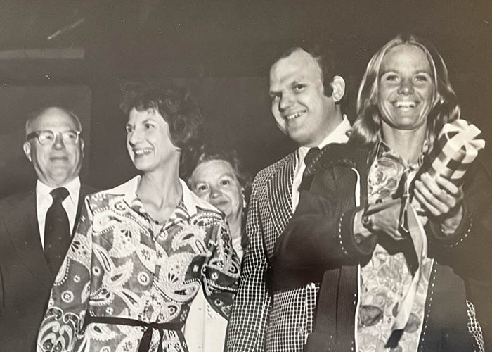 two couples smiling with one woman holding a special bottle
