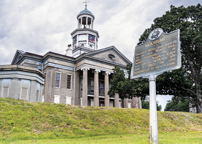 A ground-up view of the Old Courthouse Museum, a large building with two story columns by the entrance, and an open dome with a compass on the top in Vicksburg.