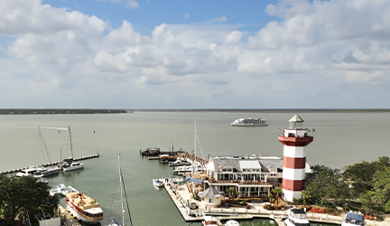 A Coastal Cat small cruise ship sailing by a port with a red and white lighthouse along the Intracoastal Waterway