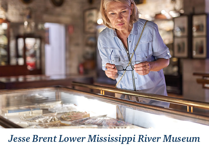 A woman looking into an exhibit at the Jesse Brent Lower Mississippi River Museum in Vicksburg. At the bottom, there is blue text overlay on a white background that reads Jesse Brent Lower Mississippi River Museum.