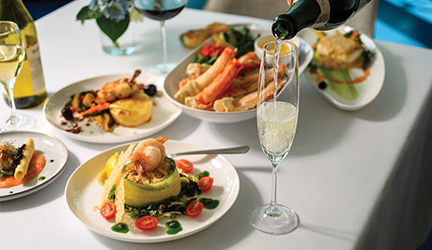 A well-decorated table displaying an array of food dishes and wine, creating an inviting atmosphere for a meal.