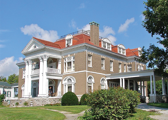 Rockcliffe Mansion, a large brown home with a burnt-orange roof, white trim, and two-story white pillars on the front porch in Hannibal.