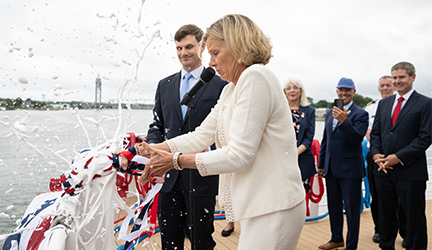 Carol Robertson christens the newest ship, the American Eagle, with foam flying through the air from a bottle of champagne.