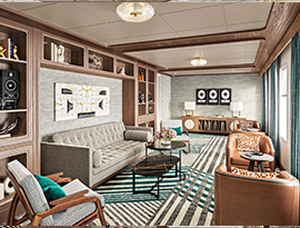 The Storyteller Lounge, a common area on American Anthem, with a tan couch against the wall with two arm chairs facing the windows directly across, and two sets of leather lounge chairs beneath the windows. On the wall above the couch, there are several shelves with miscellaneous decor. 